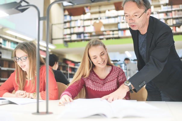 Un professeur avec des étudiantes à la bibliothèque