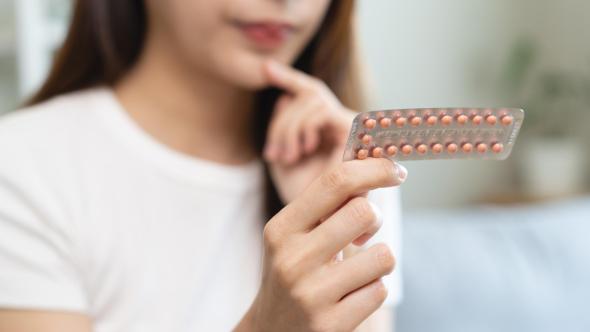 Une femme qui tient une plaquette de pilules contraceptives