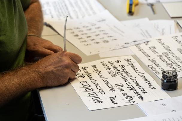 Une personne qui écrit sur un parchemin avec une encre fabriquée artisanalement Colloque-atelier parchemins et enluminures UNamur (2024)