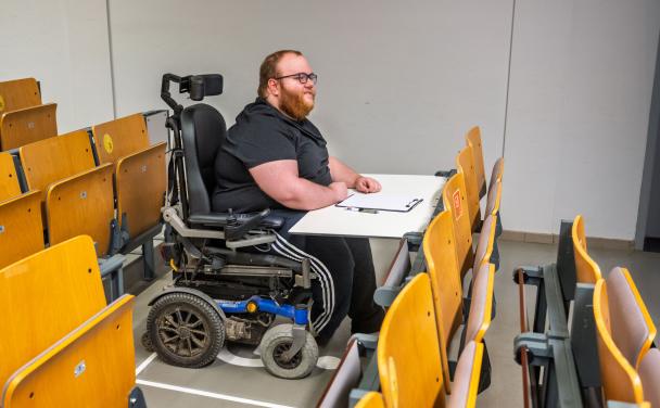 Un étudiant en chaise roulante dans l'espace auditoire prévu pour les PMR à l'Unamur