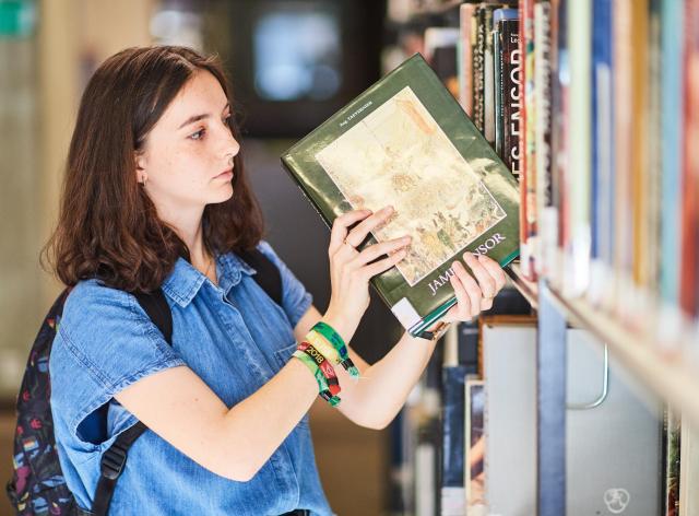 Etudiante qui prend un livre à la bibliothèque