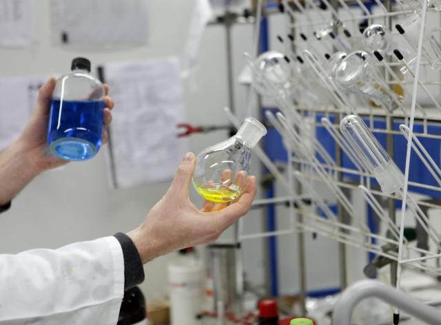 Un chimiste dans un laboratoire, qui manipule des fioles de prochuits chimiques