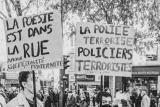 Des manifestants avec des panneaux affichant des messages "la poésie est dans la rue" et "la police terrorise, policiers terroristes"