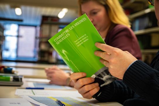Photo d'une personne feuilletant le livre "Combattre les violences sexuelles"