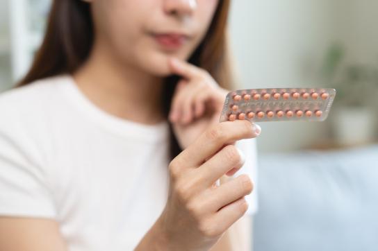 Une femme qui tient une plaquette de pilules contraceptives